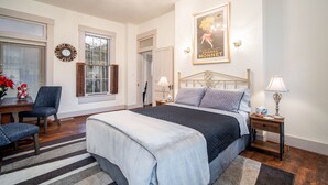 A bedroom with a bed, a desk, a chair, a nightstand, and a chandelier. - Historic Oregon District (Dayton)