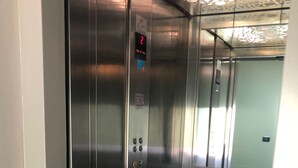 Un ascensor con paredes de acero inoxidable, una pantalla digital y un panel de control con botones.