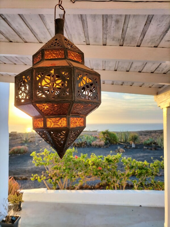 A hanging lantern with intricate cut-out patterns, suspended under a wooden ceiling. - Ocean - Volcano House (Guatiza)