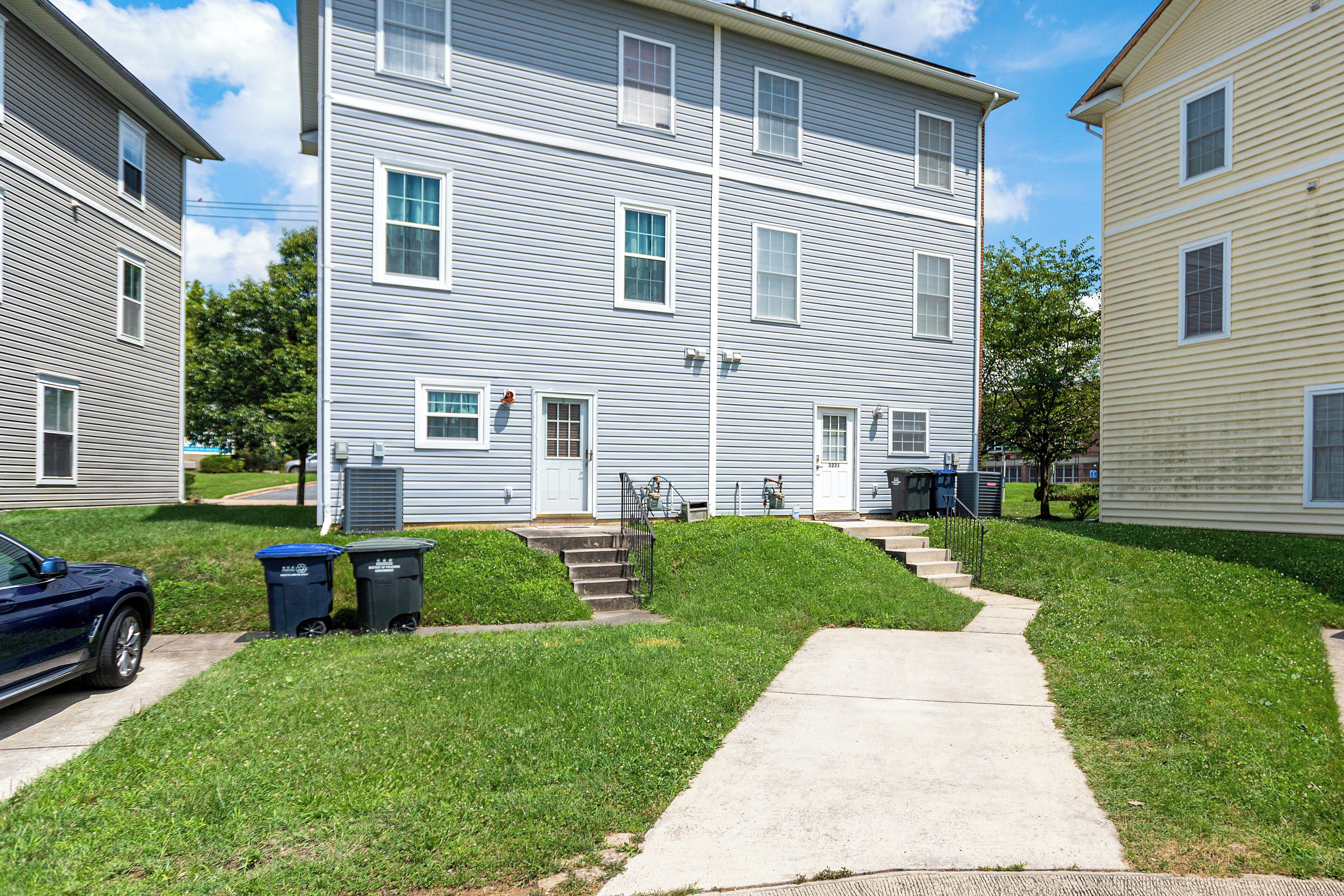 A residential building with a front yard, a driveway, and a parked car.