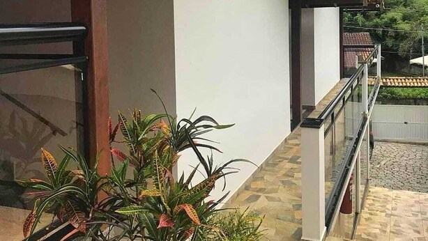 A building with a tiled roof, a small window, and a balcony with a railing. - São Pedro da Serra (Nova Friburgo)