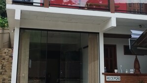 A two-story building with a glass entrance, a sign reading "RECEPCAO," and a stack of Heineken beer boxes outside. - São Pedro da Serra (Nova Friburgo)