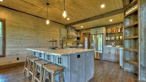Un'ampia cucina con un'isola grande, sgabelli da bar in legno ed elettrodomestici moderni.