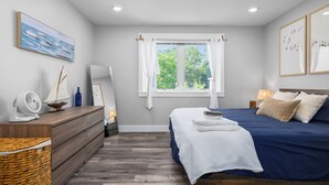 Un dormitorio con una cama grande, un aparador, una ventana con cortinas y un cuadro en la pared.