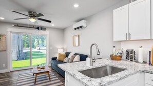 Una cocina moderna con encimera de granito, pileta de acero inoxidable y muebles color blanco.