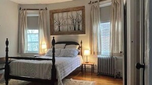 Ein Schlafzimmer mit einem Himmelbett, einem Deckenventilator, einem Heizkörper und einem fenster mit Vorhängen.
