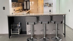 A modern kitchen with a granite countertop, three bar stools, and a built-in wine cooler. - Nice Apartment Perfect Location Ext View. (Ciudad de México)
