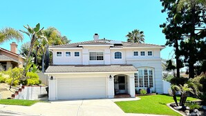 A two-story house with a garage, a covered front porch, and a well-maintained lawn. - Spacious Poolside Oasis - Right Next to Beach and Legoland (Vista)