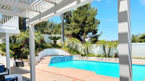 A pool area with a pergola, steps leading to the pool, and surrounding greenery. - Spacious Poolside Oasis - Right Next to Beach and Legoland (Vista)