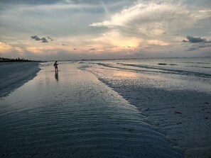 Une plage où une personne se promène le long du rivage.