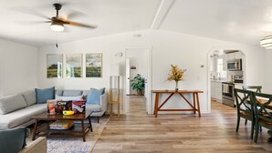 A spacious living room with a sofa, coffee table, and a dining area with chairs.