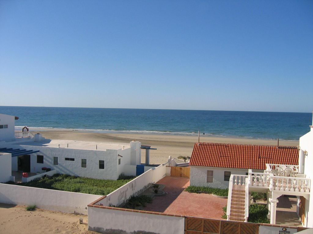 Ein Küsteneigentum mit Blick auf den Strand, weißen Gebäuden und einem Gebäude mit rotem Dach.