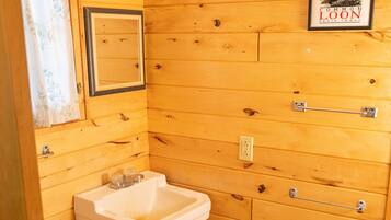A wooden bathroom with a sink, toilet, and a framed sign on the wall.