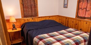 A bedroom with a bed, a nightstand, and a lamp. Text indicates guests must bring their own bedding, towels, and kitchen towels. - Webb Lake, Hackensack, Northern MN - 2 Bedroom, Sleeps 4 - Cabin #4 Blue Water (Hackensack)