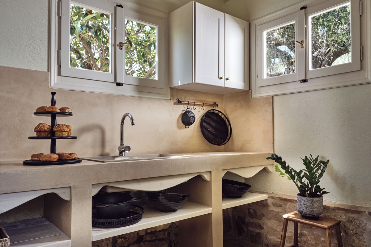 A kitchen with a three-tiered serving tray, a sink, and a hanging pot rack.