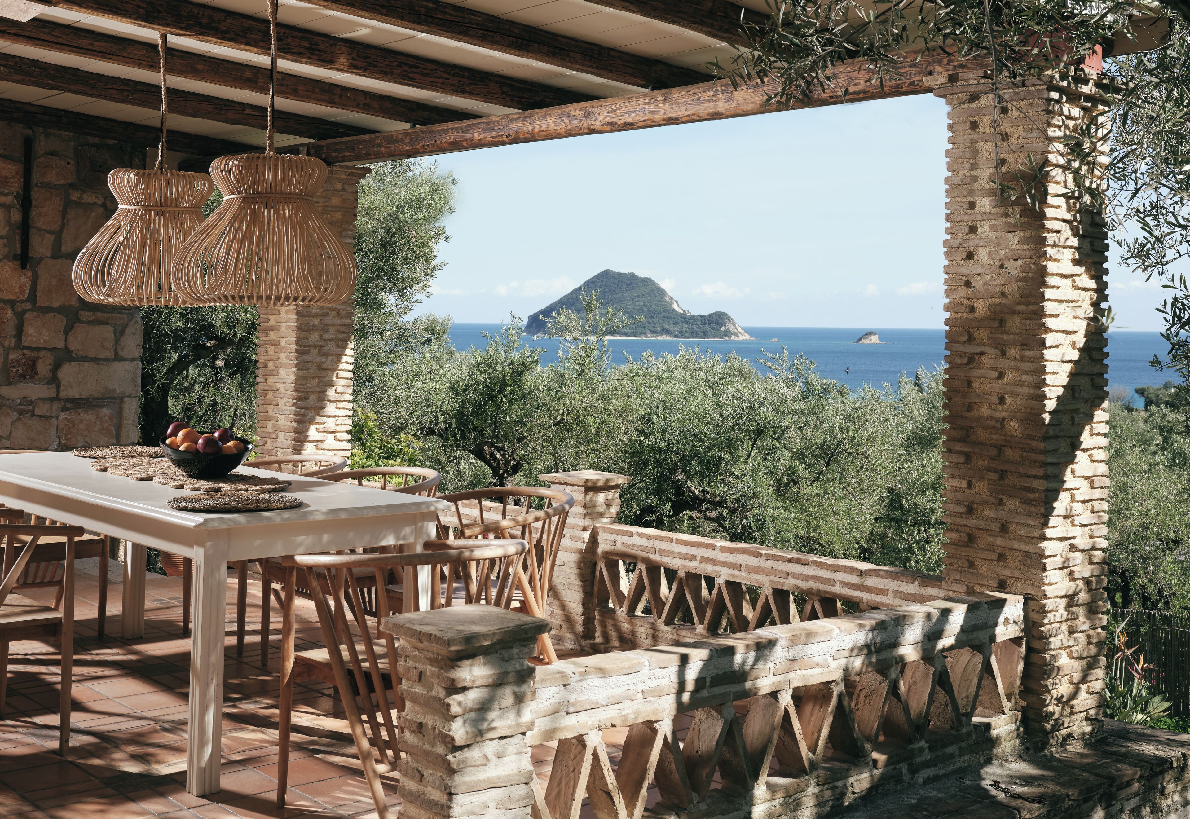 Un área de comedor al aire libre con vista al mar y una isla distante.
