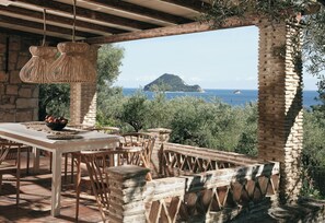 Un área de comedor al aire libre con vista al mar y una isla distante.