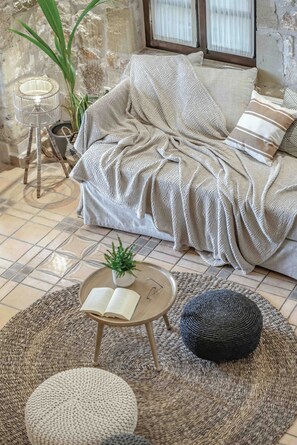 Una sala de estar acogedora con un sofá, una mesita redonda con un libro y una planta en maceta.