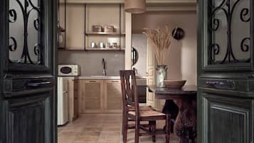 A kitchen with a wooden table, chairs, a microwave, and a vase with dried plants.