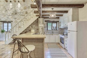 Una cocina con armarios blancos, una escalera de madera y un comedor con una mesa y sillas.