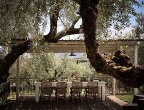 An outdoor dining area with a pergola, wicker chairs, and a table set for four. - Leeda's Villas (Zakynthos)