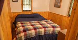 A room with a bed, wooden walls, and a window with a curtain. Text advises guests to bring their own bedding and towels. - Webb Lake, Hackensack, Northern MN - 3 Bedroom, Sleeps 6 - Cabin #3 Blue Water (Hackensack)