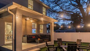 A covered outdoor seating area with a sofa, chairs, and a table.