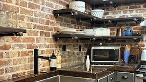 Une cuisine avec un mur en briques, des appareils électroménagers en acier inoxydable et des étagères en bois.