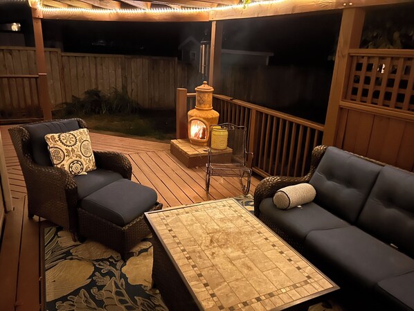 An outdoor deck with a fireplace, two sofas, and a table.