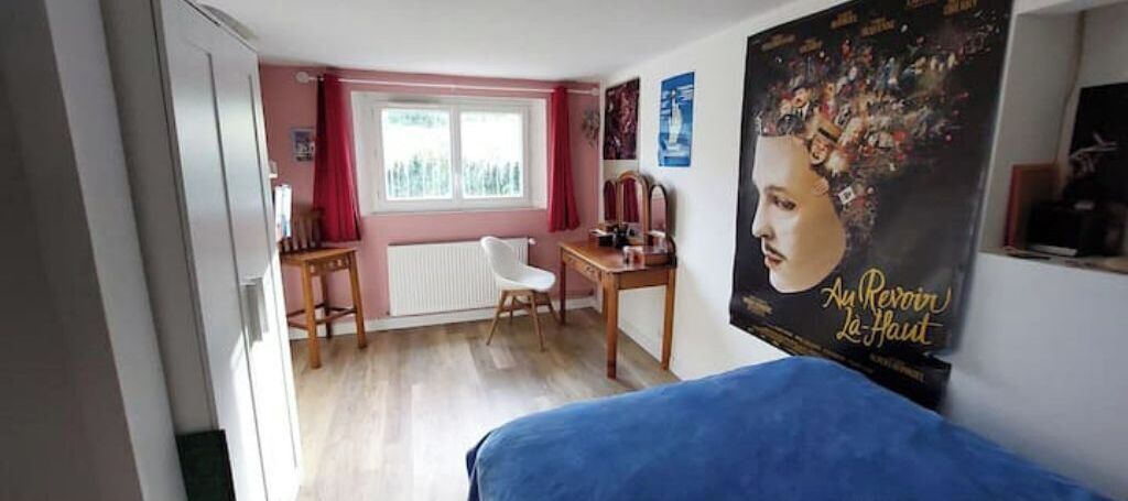 Una camera da letto con un letto, una scrivania, una sedia, un termosifone e un quadro appeso al muro.