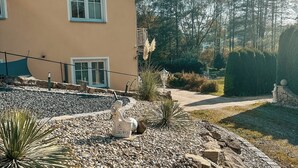 A building with a balcony, a garden with pebbles and plants, and a clear sky. - Panorama retreat; incl. private whirlpool (Bad Kötzting)
