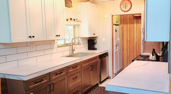 A kitchen with white cabinets, a stainless steel sink, a coffee maker, a refrigerator, and a stove. - Rustic Lakeview Lodge at Bass Lake. Bookable boat slip! (Bass Lake)