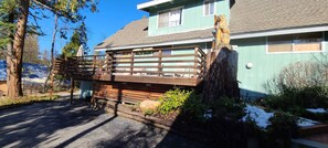 A wooden deck attached to a building with a sloped roof, surrounded by trees and a snow-covered ground. - Rustic Lakeview Lodge at Bass Lake. Bookable boat slip! (Bass Lake)