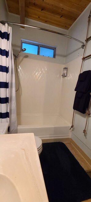 A compact bathroom with a shower, toilet, and a window above the shower. - Rustic Lakeview Lodge at Bass Lake. Bookable boat slip! (Bass Lake)