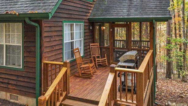 Eine Holzhütte mit einer Terrasse, Schaukelstühlen und einem Grill.