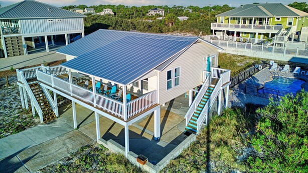 A beachfront property with a covered deck, a swimming pool, and a solar panel roof. - Beach Shack - Across Street From Beach, Private Swimming Pool, Pet Friendly! (St. George Island)