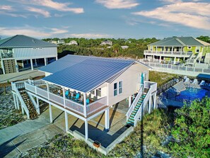 A beachfront property with a covered deck, a swimming pool, and a solar panel roof. - Beach Shack - Across Street From Beach, Private Swimming Pool, Pet Friendly! (St. George Island)