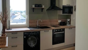 Eine moderne Küche mit eingebauter Waschmaschine und Trockner, einer Mikrowelle und einer Kaffeemaschine.