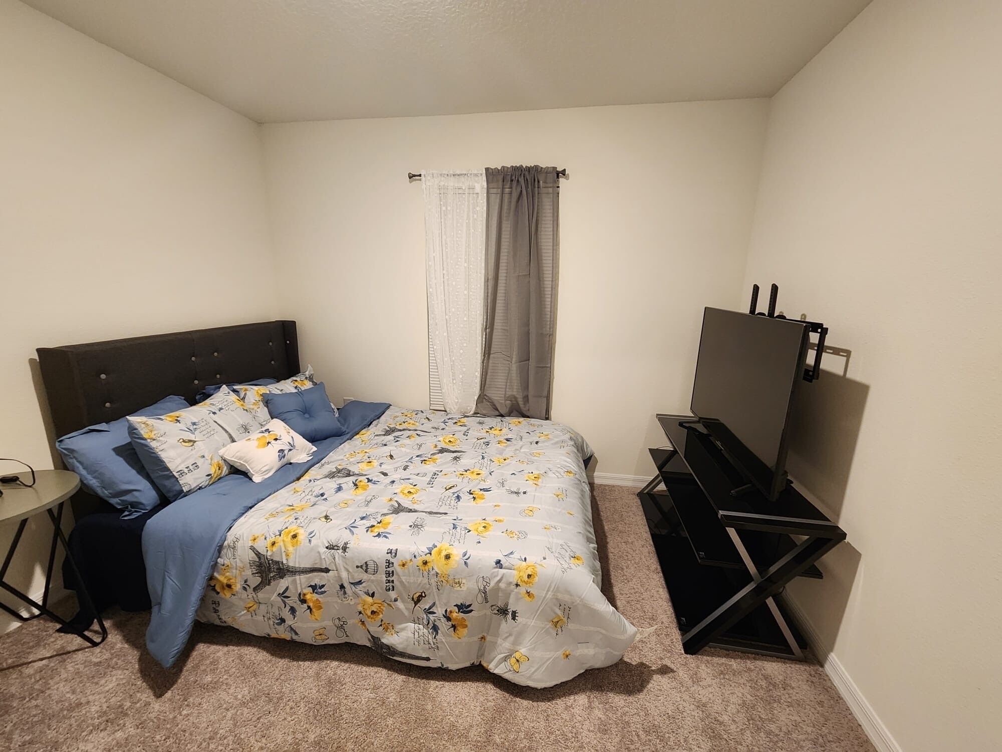 A bedroom with a bed, a desk, and a TV.