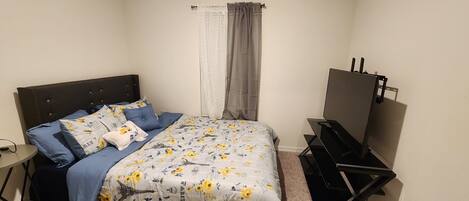 A bedroom with a bed, a desk, and a TV.