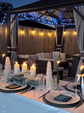An outdoor dining area with a covered patio, wooden walls, string lights, and a table set for a meal. - Happy, Luxury and Fun Space. Mins to NRG, MedCntr and downtown Houston  (Houston)