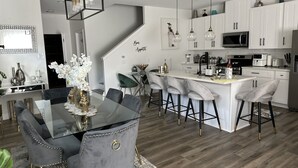 A modern kitchen with white cabinets, a central island with bar stools, and pendant lighting. - Happy, Luxury and Fun Space. Mins to NRG, MedCntr and downtown Houston  (Houston)