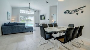 Una sala de estar moderna con sofá, mesa de comedor, sillas y televisor.