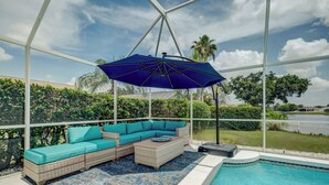 Un área junto a la piscina con zona de estar cubierta, una piscina y vistas del paisaje circundante.