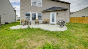 Een huis met twee verdiepingen, voorzien van een terras met buitenmeubilair en een barbecue.
