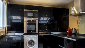 A compact kitchen with a washing machine, a microwave, and a built-in oven. - Housing San Lorenzo by Sharing Co (Málaga)