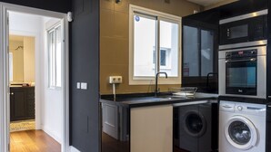 A compact kitchen with a built-in washer and dryer, a microwave, and a window with a view. - Housing San Lorenzo by Sharing Co (Málaga)