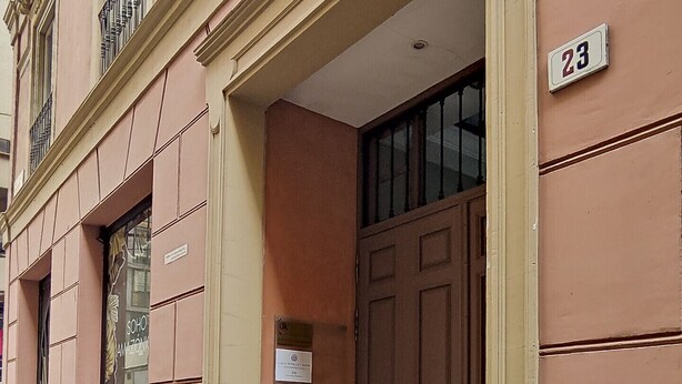 A building with a large brown door, a number '23' sign, and a small window with a sign above it. - Housing San Lorenzo by Sharing Co (Málaga)