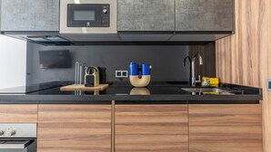 Una cocina moderna con microondas integrado, electrodomésticos de acero inoxidable, armarios de madera y encimera negra.