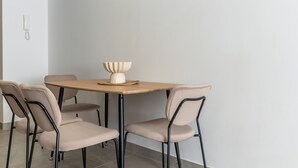 Comedor con mesa de madera y cuatro sillas, un jarrón sobre la mesa y un teléfono en la pared.